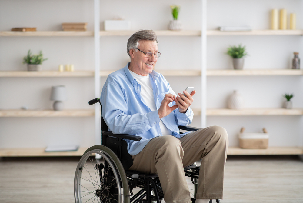 Positive,Senior,Impaired,Man,In,Wheelchair,Checking,Messages,Or,Watching