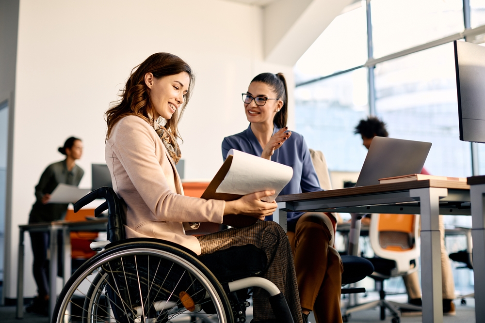Happy,Businesswoman,In,Wheelchair,Going,Through,Reports,While,Talking,To
